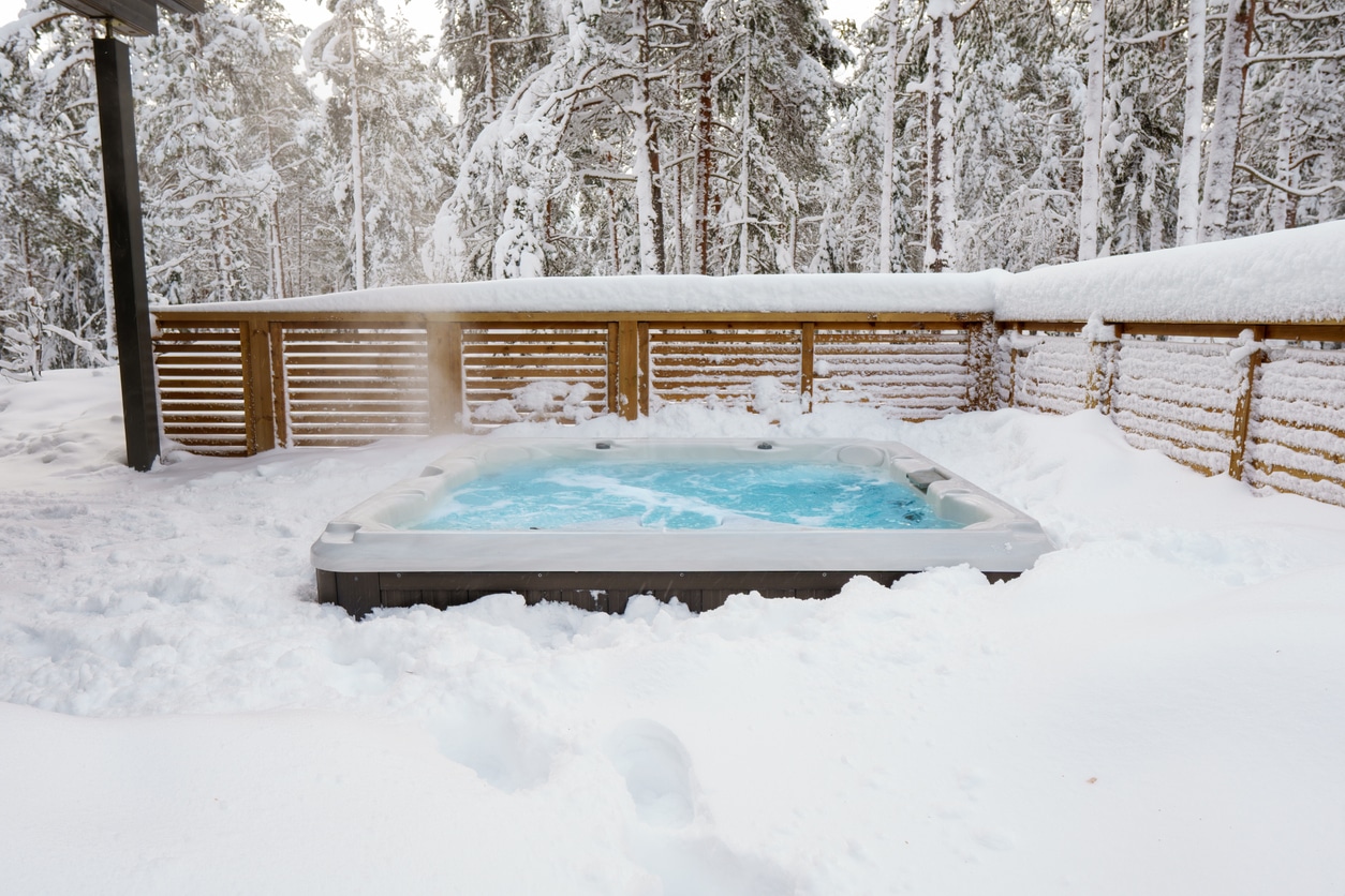 Warm hot tub in beautiful winter landscape with snow slowly falling down